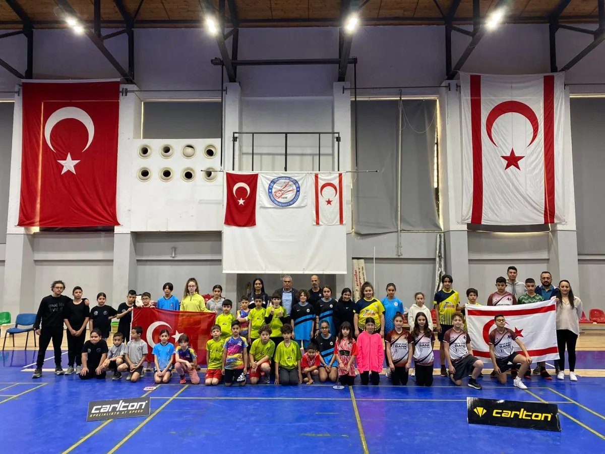 Children, families and coaches at the 23 April U13 Open tournament in a group photo in front of flags